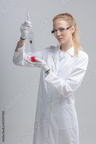 Chemical test tubes and flasks with petroleum products, the girl is a laboratory assistant, safety glasses. white gloves. measuring cylinder, hydrometer