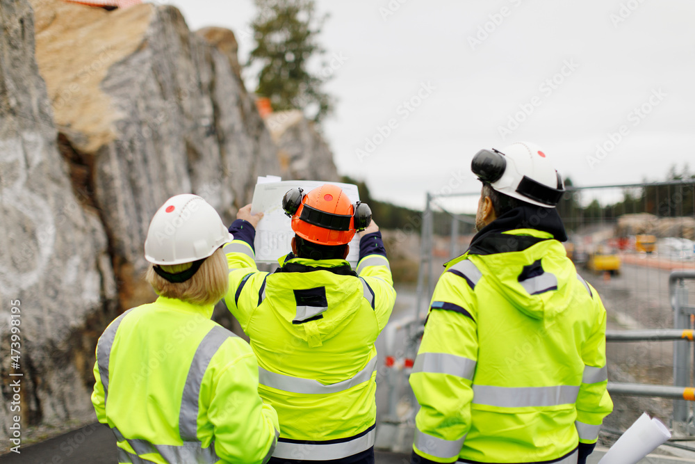 Engineers in reflective clothing discussing plans Engineers in reflective clothing discussing plans