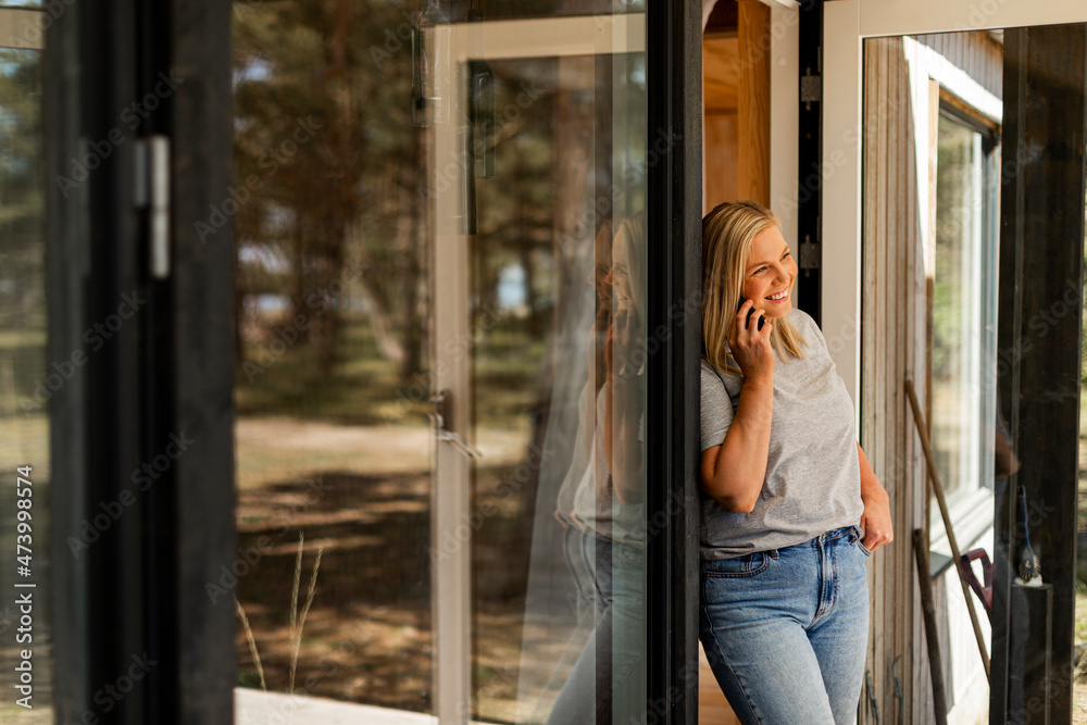 Woman standing on patio and talking via cell phone Woman standing on patio and talking via cell phone
