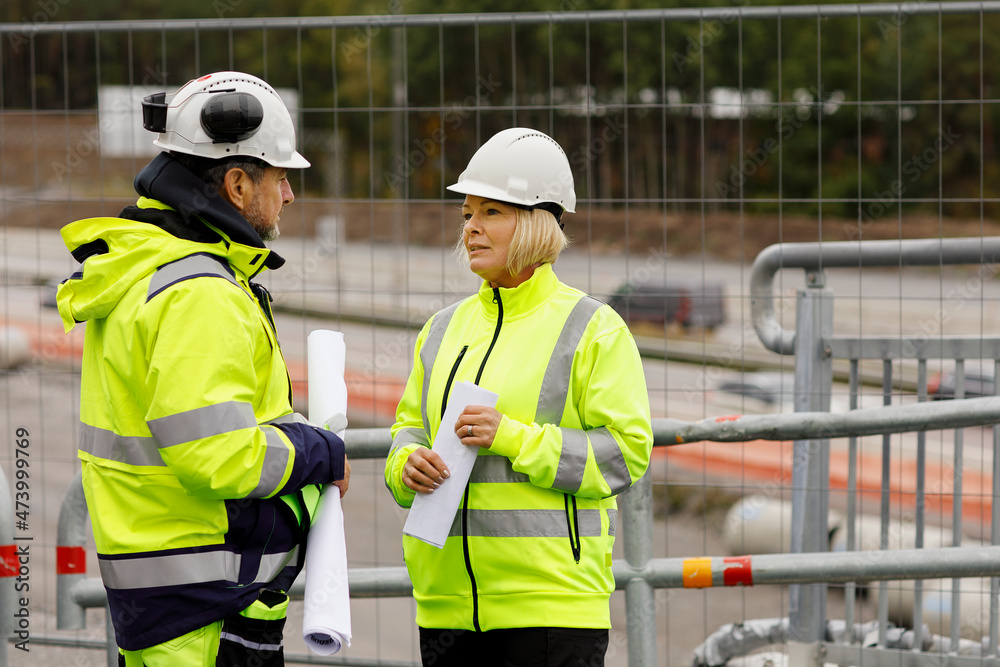 Engineers in reflecting clothing talking at building site Engineers in reflecting clothing talking at building site