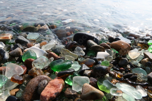Canvas Print colourful shards of glass polished by sea on a smooth stone, small glass pieces
