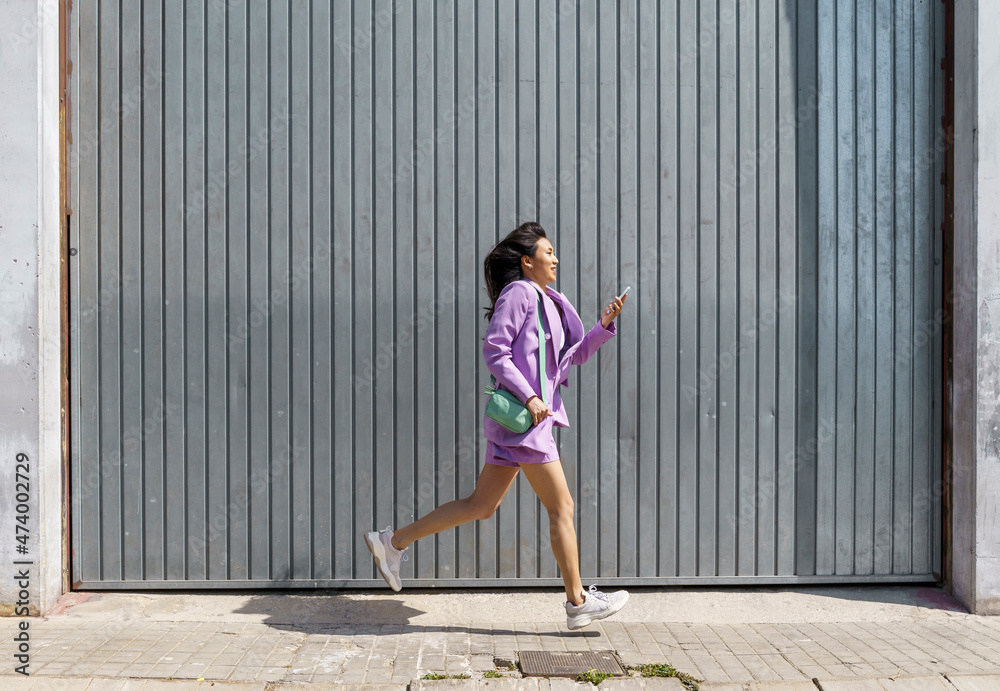 Mid adult woman running by gray wall Mid adult woman running by gray wall