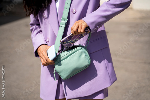 Mid adult woman keeping mobile phone in purse during sunny day photo
