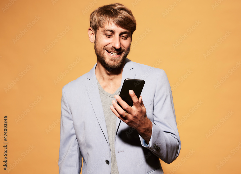 Smiling man with blond hair looking at mobile phone Smiling man with blond hair looking at mobile phone