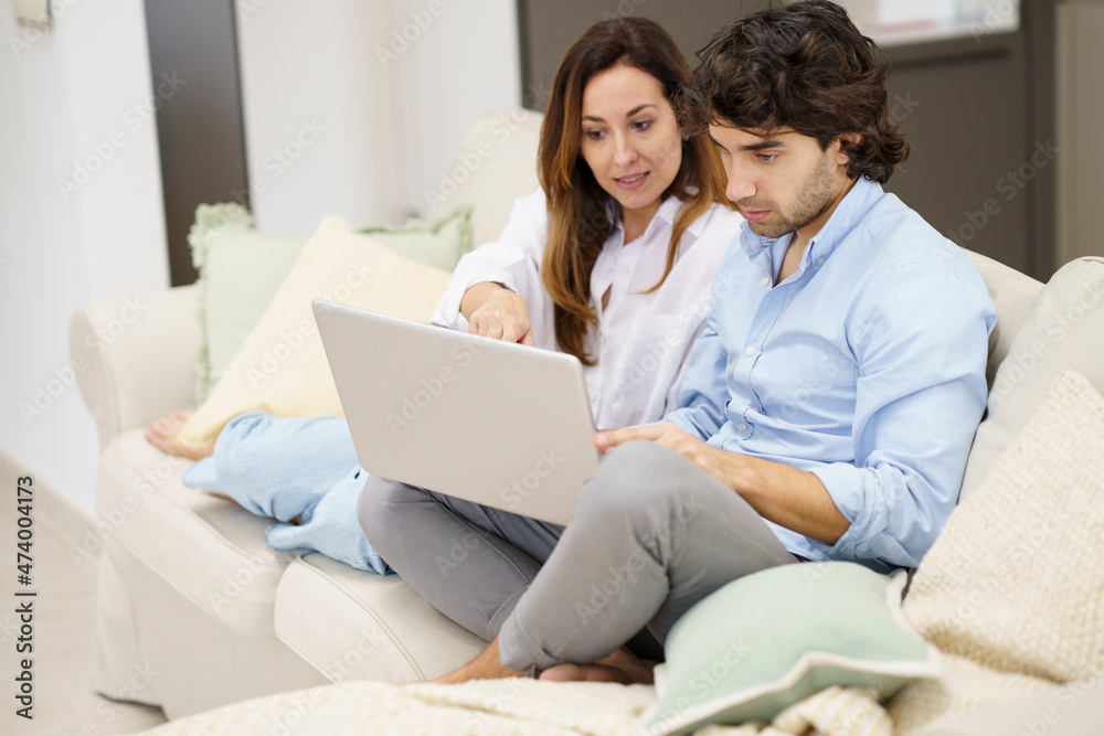 Couple talking while watching on laptop at new home Couple talking while watching on laptop at new home
