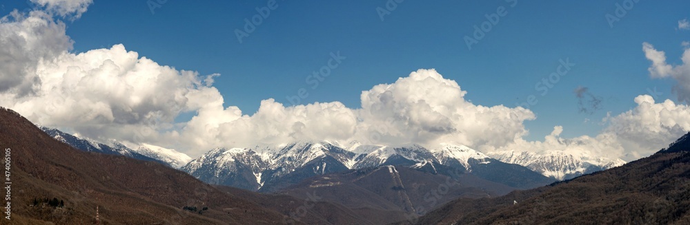 Panoramic view of snow capped mountains in the clouds. Caucasian mountains. Sochi Krasnaya Polyana. Russia.