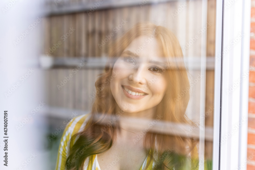 Beautiful smiling redhead woman seen through window Beautiful smiling redhead woman seen through window