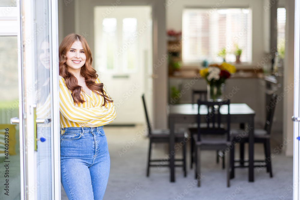 Smiling redhead woman standing with arms crossed by window Smiling redhead woman standing with arms crossed by window
