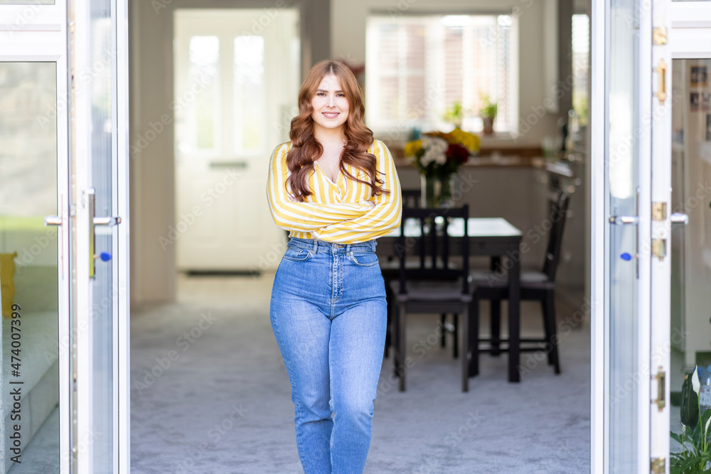 Beautiful smiling redhead woman standing with arms crossed at window Beautiful smiling redhead woman standing with arms crossed at window