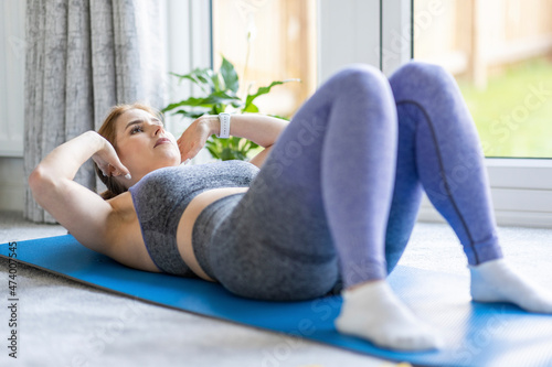 Mid adult woman practicing crunches while exercising at home photo