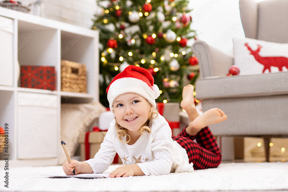 Cute little girl writing letter to Santa in decorated living room