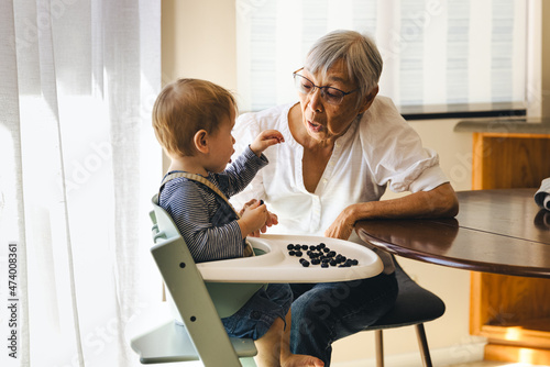 Grandmother With Grandson Eating Fruit At Home
