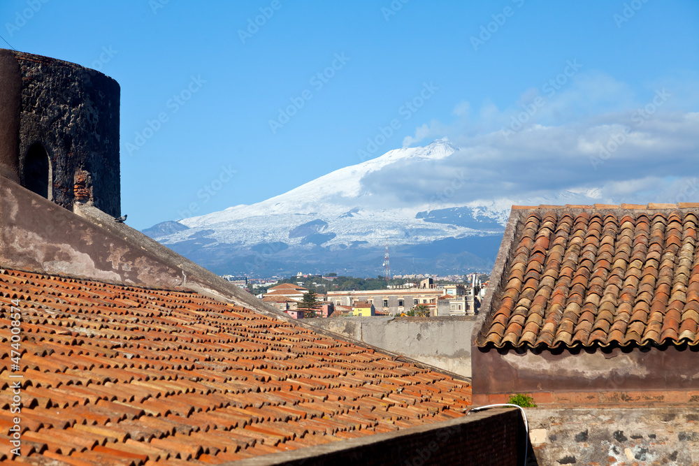 Panoramic view over Catania with the snowy volcano Etna behind city houses