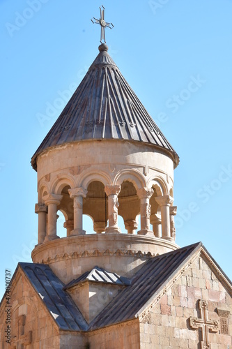 View of the building of the old monastery. A bell tower with carved columns and a conical roof with a cross.