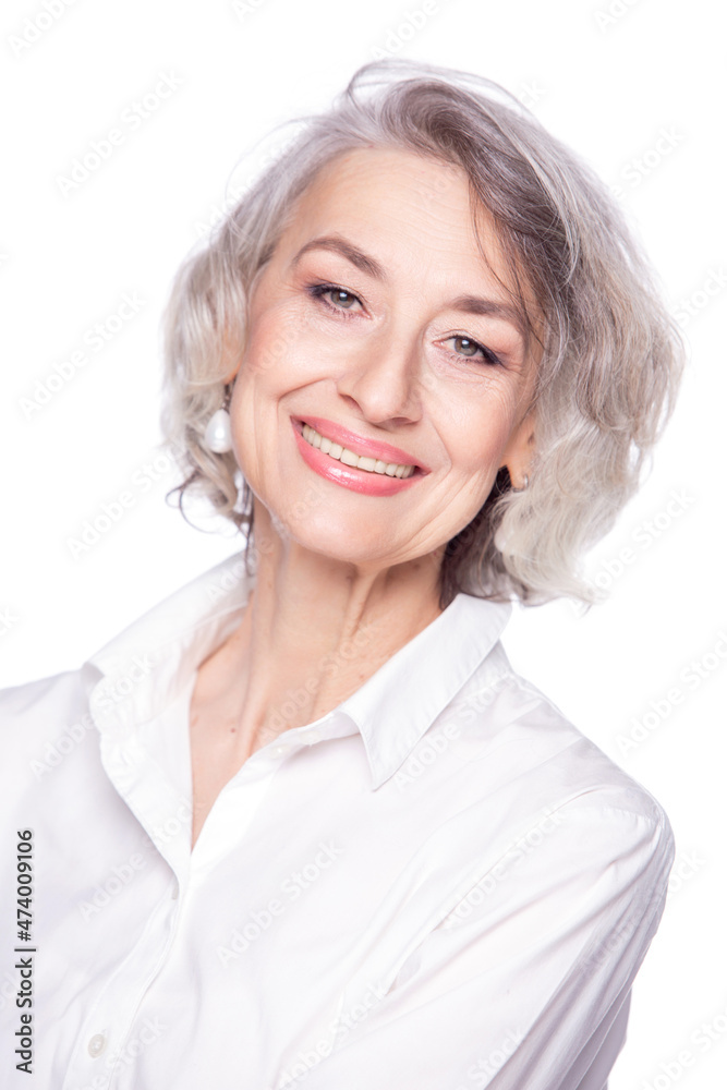 Close up portrait of pleasant grey-haired middle aged female looking at camera with a wide smile and showing happiness, isolated on white studio background