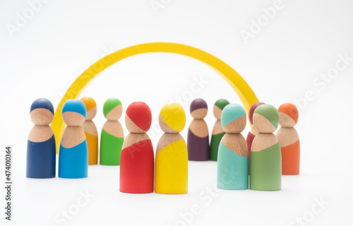 Wooden people of different colors together on endless white background.