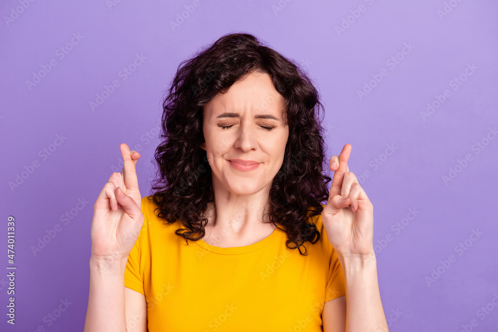 Photo of young attractive woman crossed fingers beg wish luck success isolated over violet color background Photo of young attractive woman crossed fingers beg wish luck success isolated over violet color background