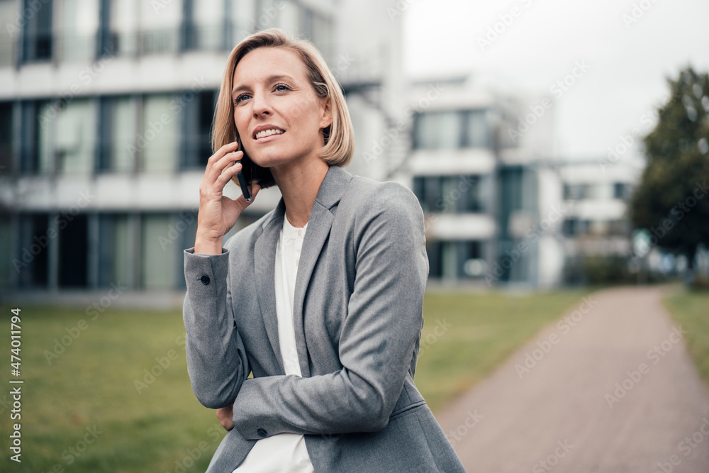 Female entrepreneur talking on mobile phone while standing at office park Female entrepreneur talking on mobile phone while standing at office park