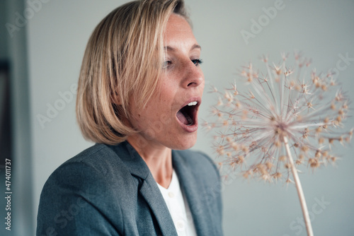 Businesswoman with mouth open looking at flower decor in office