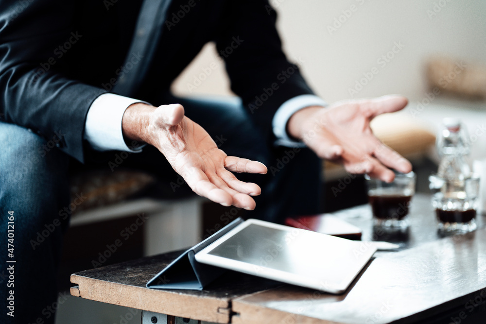 Mature businessman sitting with digital tablet gesturing while sitting in cafe