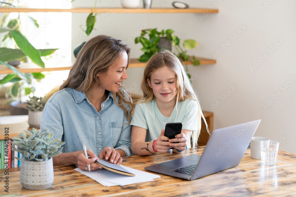 Mother looking at daughter using smart phone Mother looking at daughter using smart phone