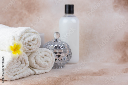 Spa still life treatment composition on massage table in wellness center. Twisted hot towel with aromatic candles on beige background. Aroma therapy setting. Concept of harmony  balance and meditation