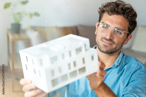 Male entrepreneur with eyeglasses holding architectural model in office photo