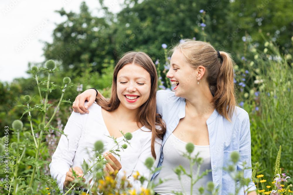 Cheerful young woman with arm around friend amidst plants in nature Cheerful young woman with arm around friend amidst plants in nature