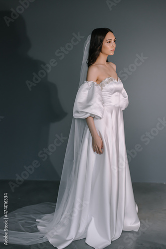Slim beautiful woman with long hair wearing luxurious wedding dress isolated on background
