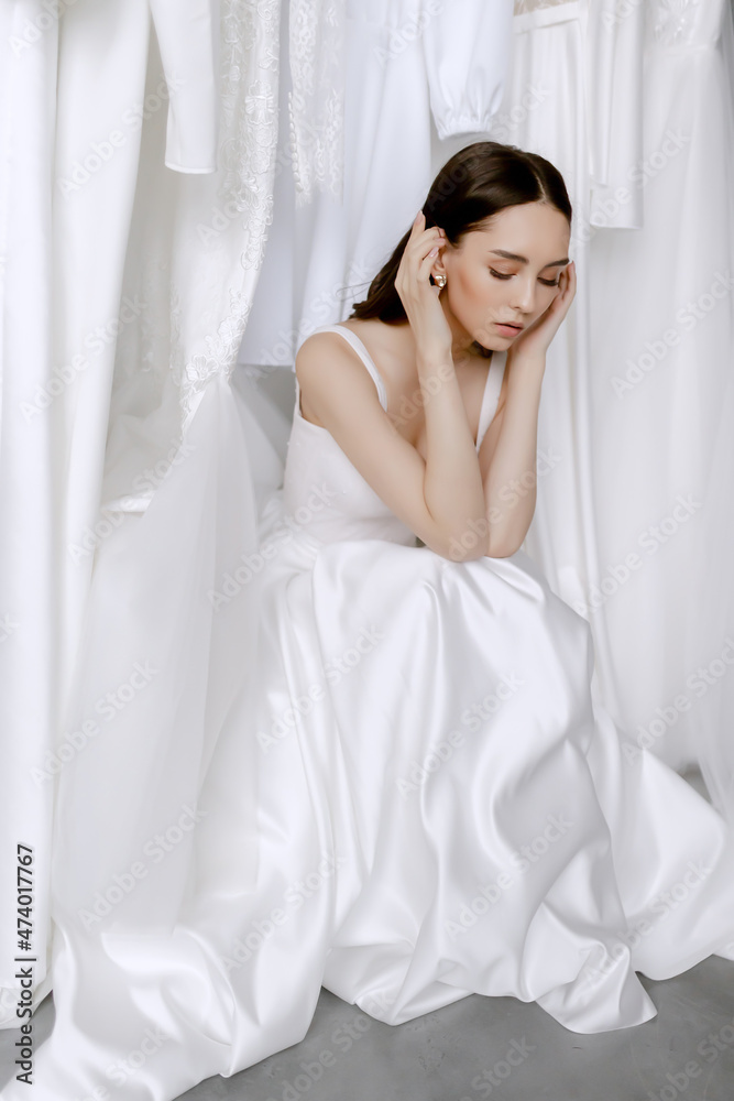 Young beauiful happy bride wearing white wedding dress and posing in bright empty interior Young beauiful happy bride wearing white wedding dress and posing in bright empty interior