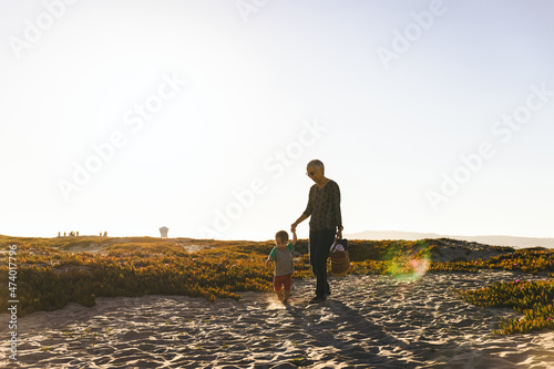 Grandmother Holding Hand Of Grandson While Walking At Beach