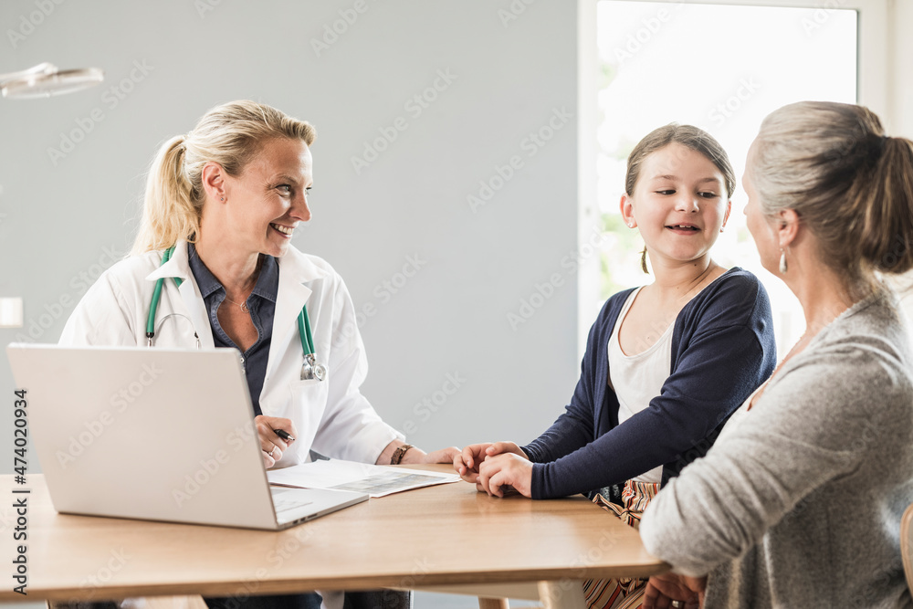 Daughter talking with mother while sitting by doctor at office Daughter talking with mother while sitting by doctor at office