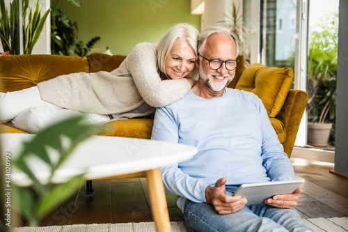 Woman leaning on shoulders of man using digital tablet at home