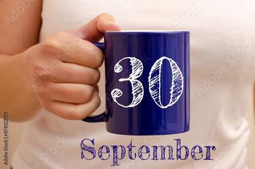 The inscription on the blue cup 30 september. Cup in female hand, business concept