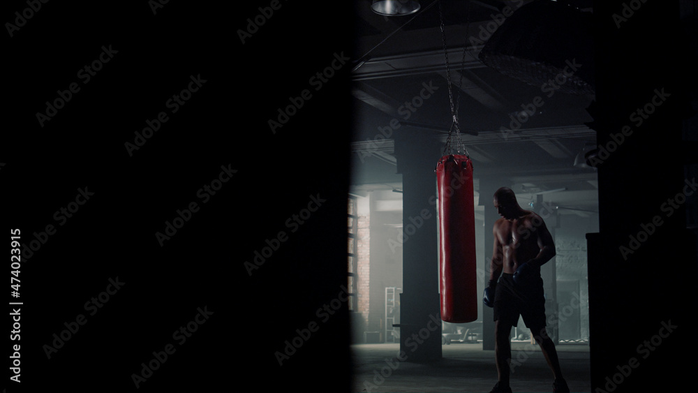 Man finishing boxing training. Boxer walking in loft building with punching bag