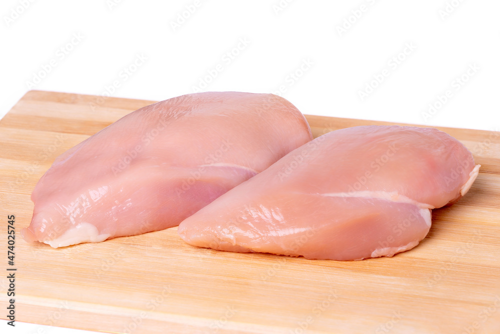 Raw chicken breast on a cutting board, white background Raw chicken breast on a cutting board, white background