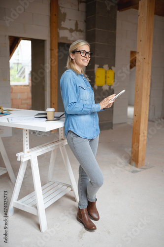 Smiling female building contractor looking away while holding at construction site