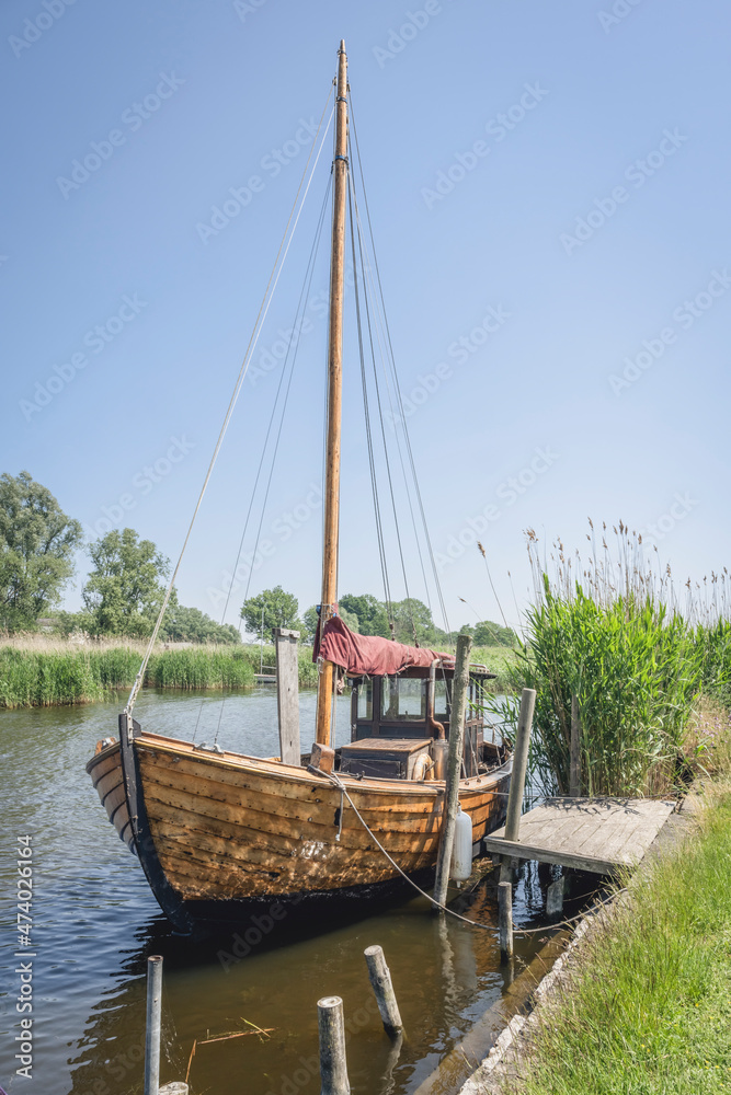 Sailboat moored at riverbank in summer Sailboat moored at riverbank in summer