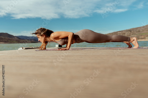 Female athlete practicing Chaturanga Dandasana on jetty photo