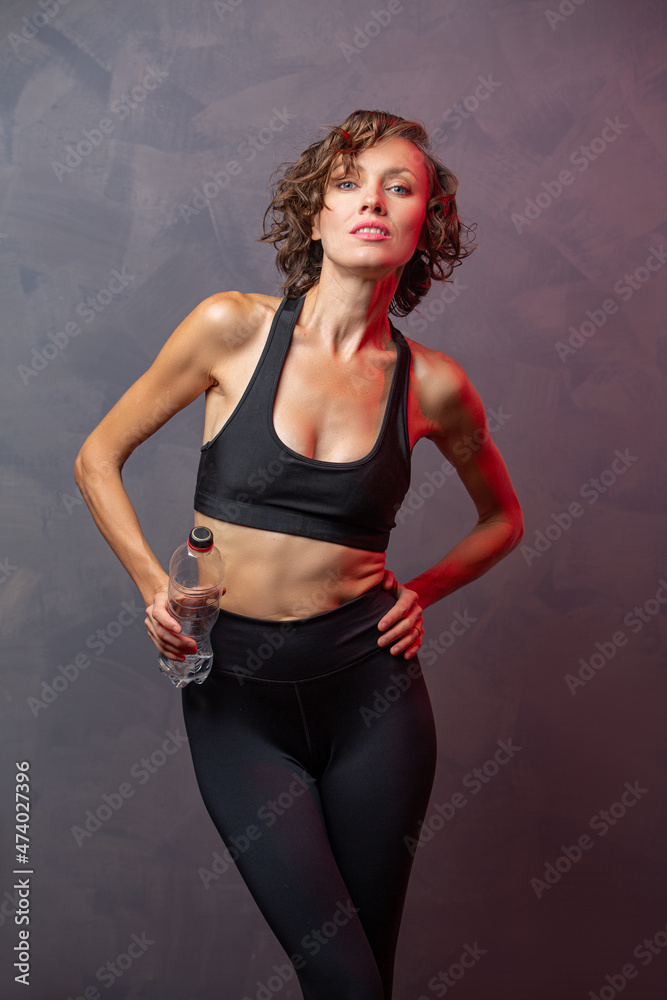 Portrait of woman taking break from working out and drink water. Sporty girl with water banner	