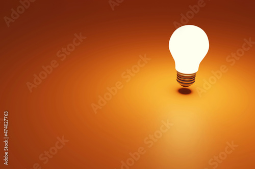 Three dimensional render of old-fashioned light bulb glowing brightly against orange background photo