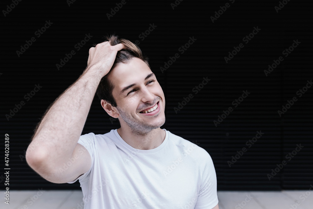 Smiling man with hand in hair looking away Smiling man with hand in hair looking away