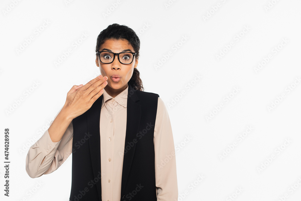 Shocked african american businesswoman in eyeglasses looking at camera isolated on white.