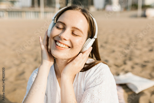 Happy woman listening music through headphones at beach photo