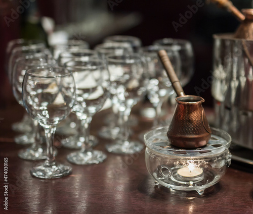 copper Turkish coffee cup stands on a wooden table in the bar in the evening in the semi-darkness, restaurant bar counter
