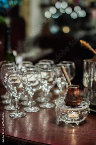 copper Turkish coffee cup stands on a wooden table in the bar in the evening in the semi-darkness, restaurant bar counter