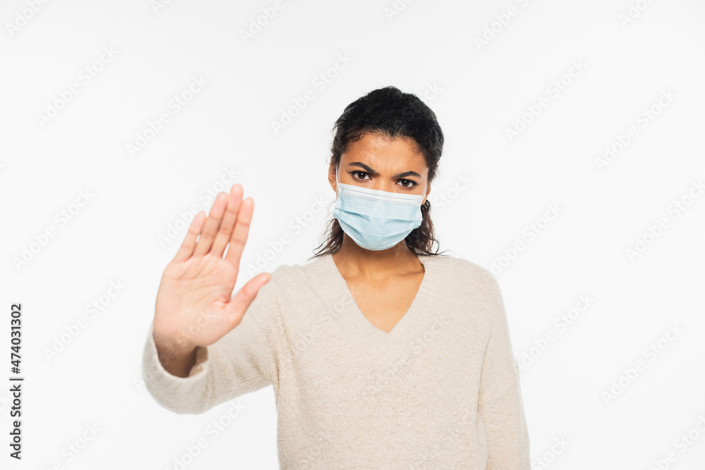 Serious african american woman in medical mask showing stop gesture isolated on white. Serious african american woman in medical mask showing stop gesture isolated on white.