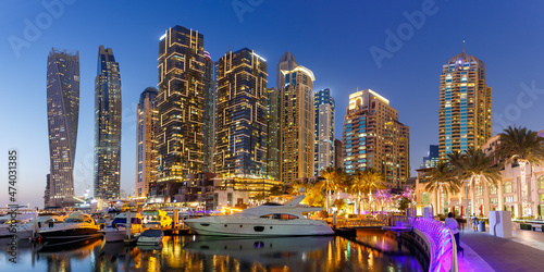 Dubai Marina and Harbour skyline architecture wealth luxury travel with yacht boat at night panorama in United Arab Emirates