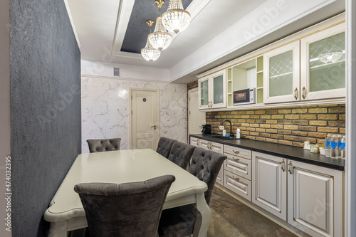 dining area in the kitchen with a large gray wall and a spacious table with armchairs upholstered in velor fabric  a kitchen area made of natural wood with imitation of natural stone