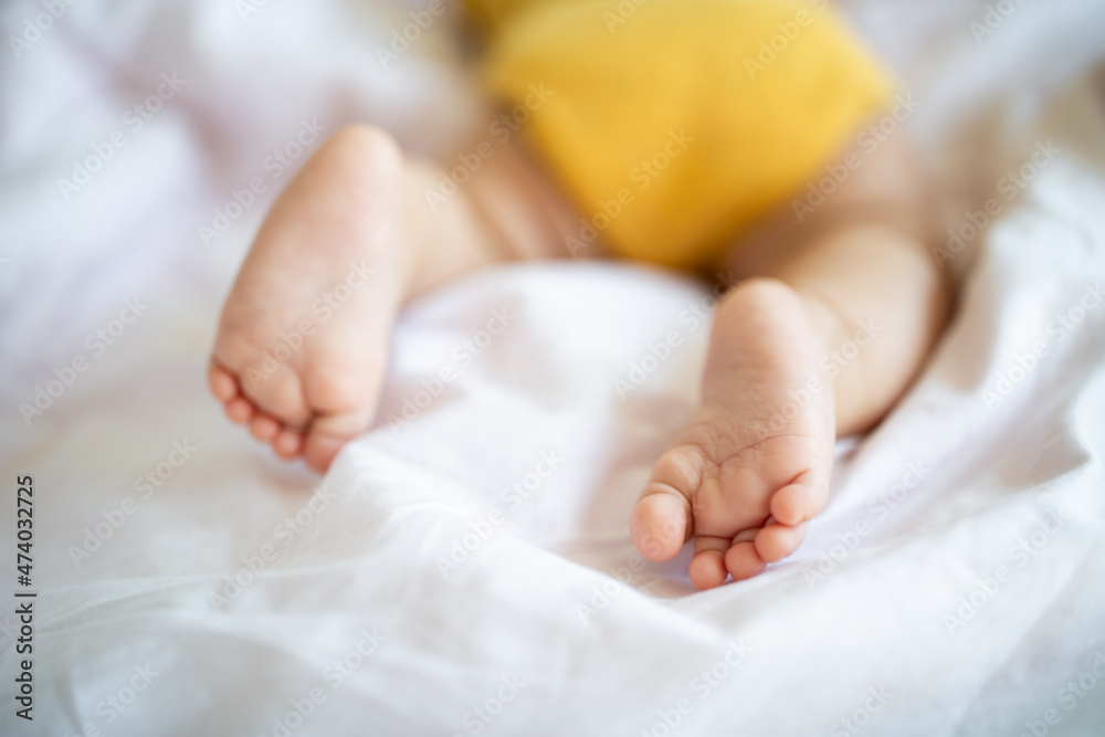 Feet of Caucasian blonde baby seven months old lying on bed at home. Kid wearing cute clothing trendy colors: illuminating yellow. Infant sleeping Feet of Caucasian blonde baby seven months old lying on bed at home. Kid wearing cute clothing trendy colors: illuminating yellow. Infant sleeping